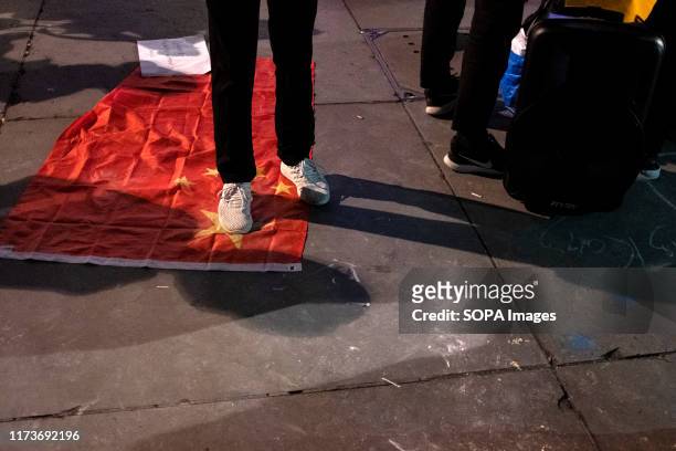 Protester walks on top of the Chinese flag during the demonstration. Protesters rallied at Trafalgar Square to demand democracy and justice in Hong...