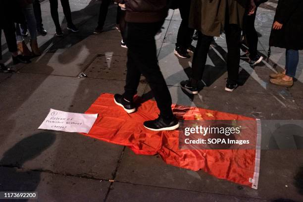 Protester walks on top of the Chinese flag during the demonstration. Protesters rallied at Trafalgar Square to demand democracy and justice in Hong...