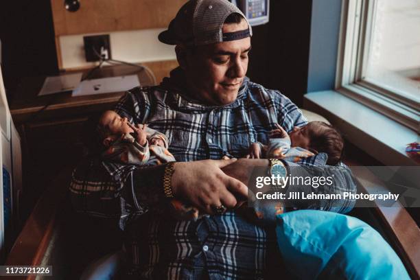 premature twins are held together by father in arms in hospital - cute twins stock-fotos und bilder