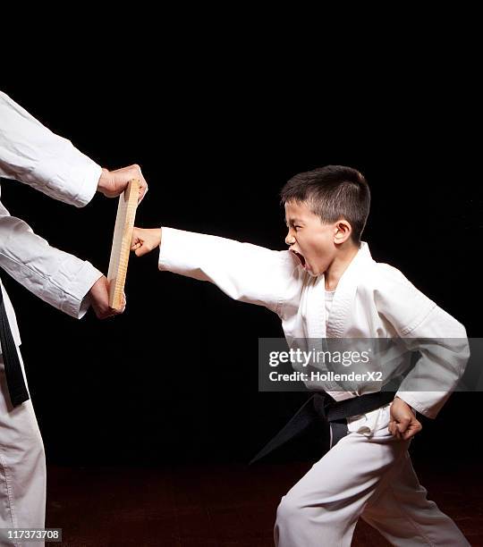 boy in karate outfit punching wood - child punching stock pictures, royalty-free photos & images