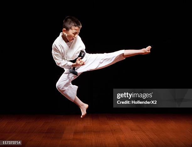 young boy with black belt in karate kicking in air - black belt martial arts stock pictures, royalty-free photos & images