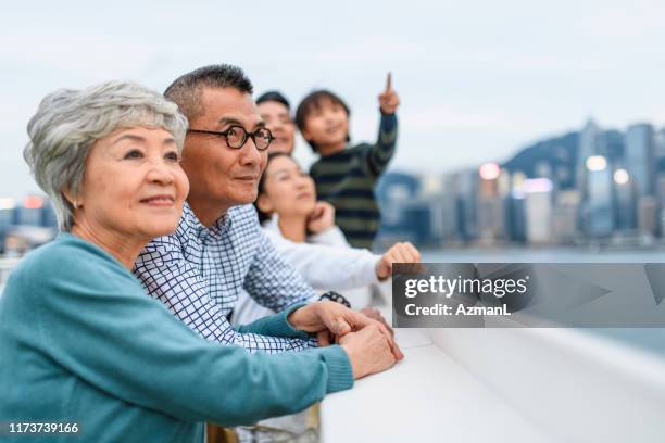 lächelndes chinesisches senior-paar genießt die aussicht auf hongkong - elderly chinese man stock-fotos und bilder