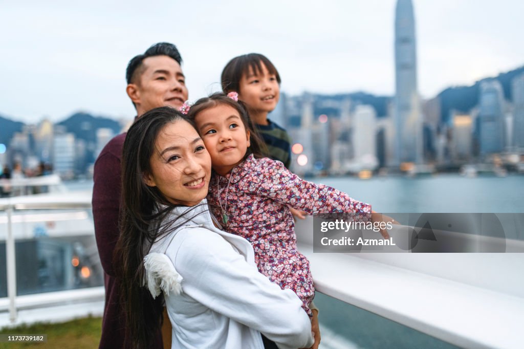 Jeune famille chinoise de sourire appréciant Hong Kong au crépuscule