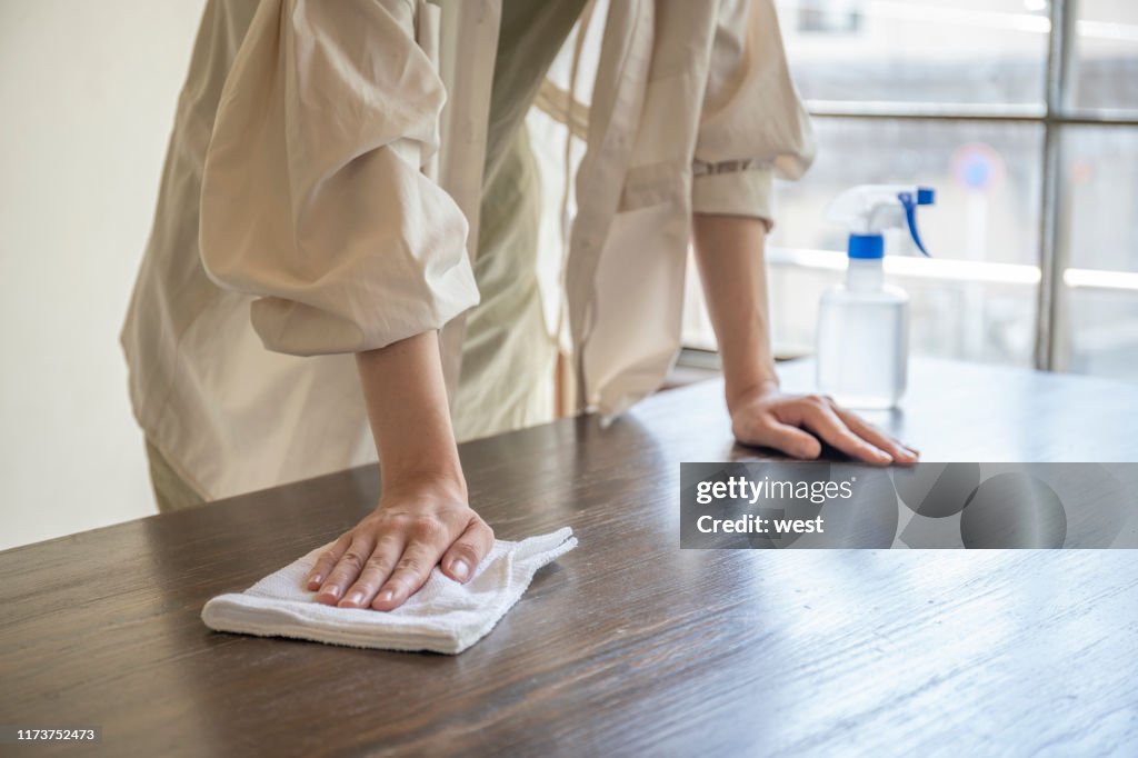 Mão da mulher que limpa a mesa