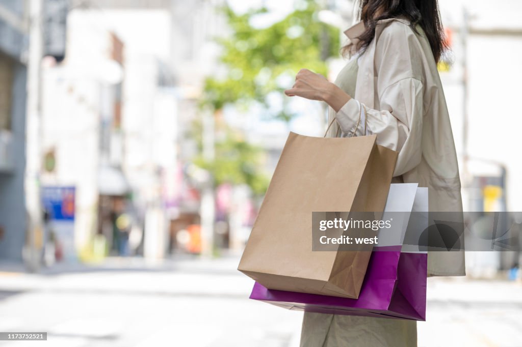 Hände der Frau mit vielen Einkaufstaschen beim Einkaufen