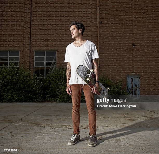 young male skateboarder standing by urban building - tshirt stock pictures, royalty-free photos & images