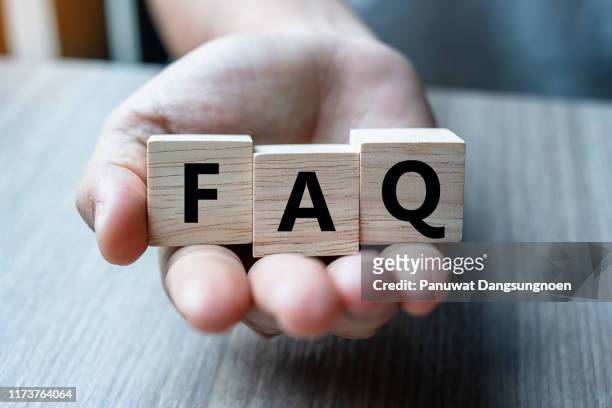 close-up of hand holding toy blocks with faq text on table - q and a stock pictures, royalty-free photos & images