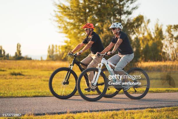senior par njuter av livet efter arbetet cykling tillsammans - elcykel bildbanksfoton och bilder