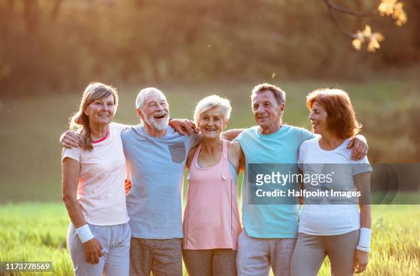 a group of active senior friends runners standing outdoors in spring nature. - arm in arm stock pictures, royalty-free photos & images