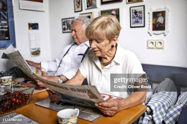 senior couple reading newspaper at home - esstisch stock-fotos und bilder