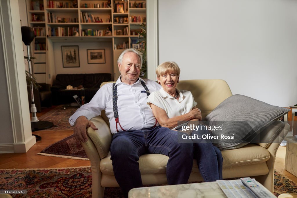 Portrait of smiling senior couple sitting on couch at home