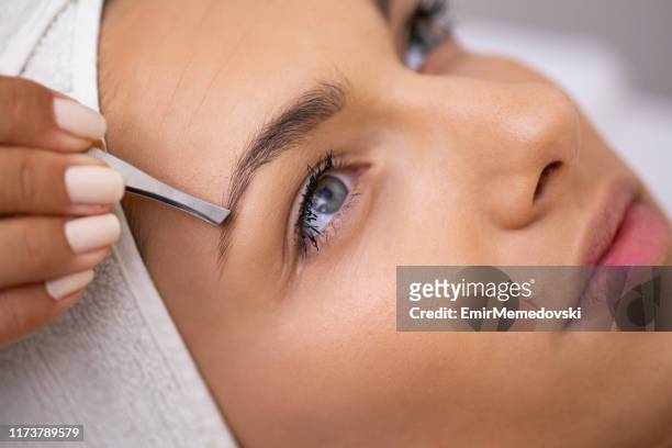 beautiful young woman gets eyebrow correction procedure - eyebrow stock pictures, royalty-free photos & images