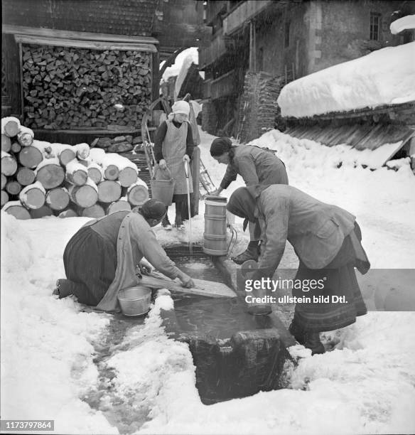 Loetschental, women clean milk churn at fountain; 1941
