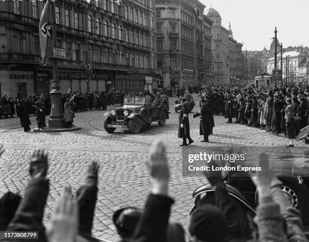 Austrian citizens give the Nazi salute as German Wehrmacht troops and artillery parade through the streets of Vienna after the German Fuhrer and...