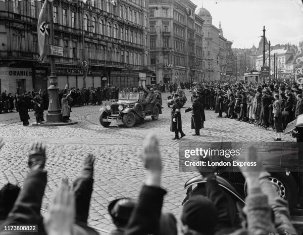 Austrian citizens give the Nazi salute as German Wehrmacht troops and artillery parade through the streets of Vienna after the German Fuhrer and...