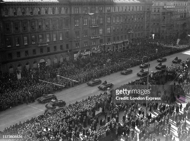 Austrian citizens give the Nazi salute as German Wehrmacht Panzerkampfwagen I PzKpfw I tank's parade through the streets of Vienna past the Cafe...