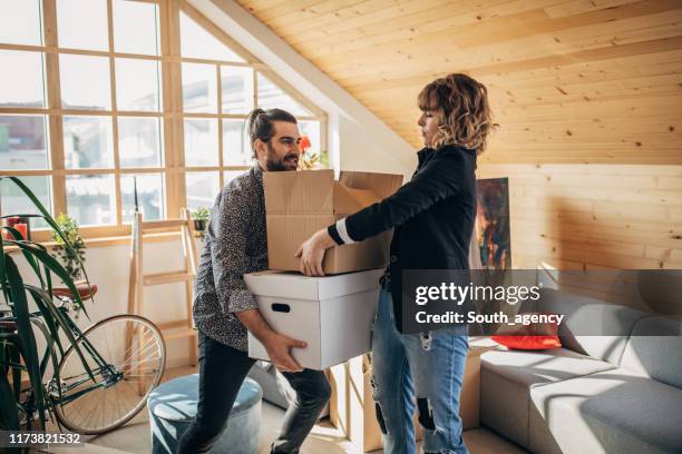 young couple unpacking boxes in new home - carrying sofa stock pictures, royalty-free photos & images