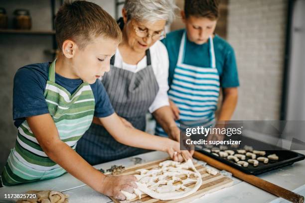 making cookies with grandma is always a great fun - grandson stock pictures, royalty-free photos & images