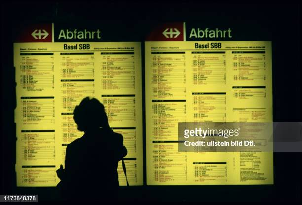 Frau vor Abfahrts-Fahrplan in Basel, 1990