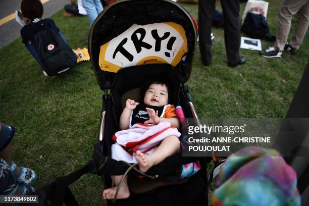 Baby lays in a stroller with a 'Try' placard