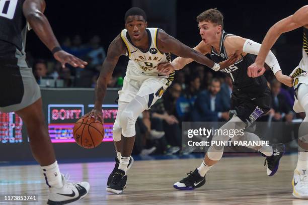 Indiana Pacers player Edmond Sumner dribbles past Sacramento Kings players during the second pre-season NBA basketball game between Sacramento Kings...