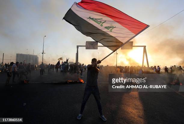 An Iraqi protester waves the national flag during a demonstration against state corruption, failing public services, and unemployment, in the Iraqi...