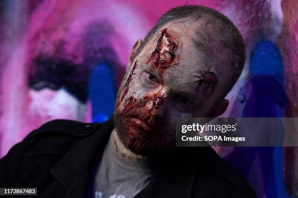 Participant seen with a painted face lying on a wall during the annual charity walk. People wearing zombie costumes gather in London to join efforts...