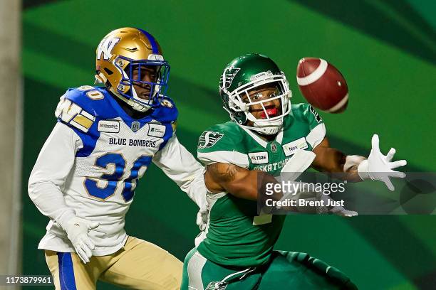 Shaq Evans of the Saskatchewan Roughriders makes a catch for a touchdown behind Winston Rose of the Winnipeg Blue Bombers that was called back on a...