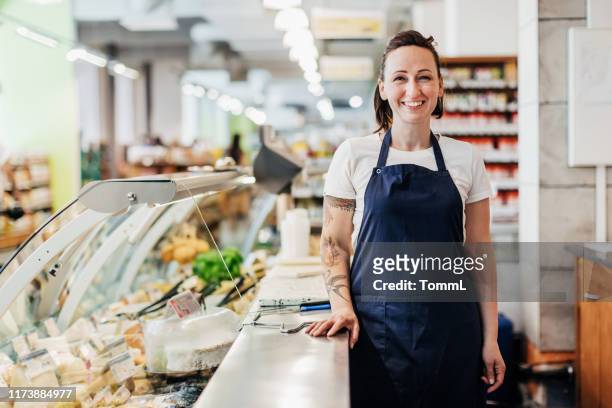 porträt von supermarkt-angestellter steht am tresen - food service occupation stock-fotos und bilder