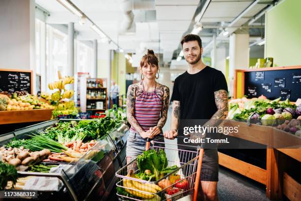 porträt von hipster paar einkaufen für lebensmittel im lokalen supermarkt - shoppen hipster stock-fotos und bilder
