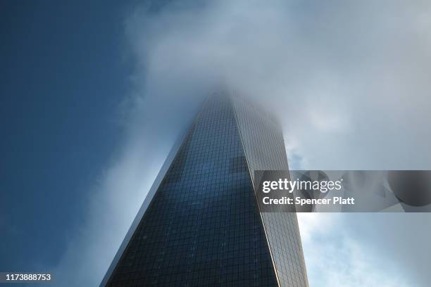 One World Trade Center, also known as the Freedom Tower, is shrouded in a cloud above the National September 11 Memorial during a morning...