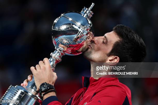 Serbia's Novak Djokovic kisses the trophy after winning the men's singles final against John Millman of Australia at the Japan Open tennis tournament...