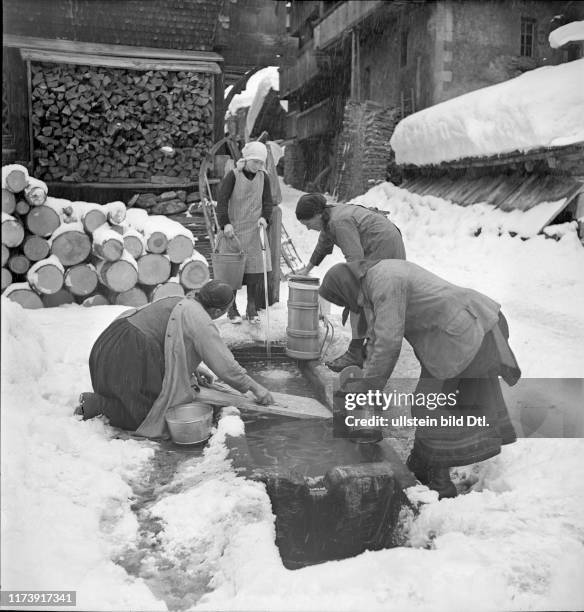 Loetschental, women clean milk churn at fountain; 1941