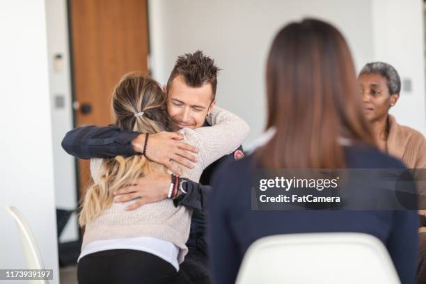 man en vrouw knuffel in groep therapiesessie - drug rehab stockfoto's en -beelden