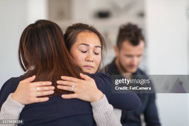 due donne si abbracciano nella sessione di terapia - addiction recovery foto e immagini stock