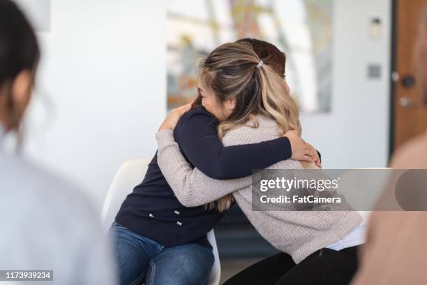 two women hug in therapy session - women hugging in group therapy session stock pictures, royalty-free photos & images