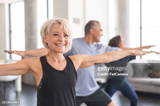 aktive senioren im gruppenfitnesskurs - yoga group stock-fotos und bilder