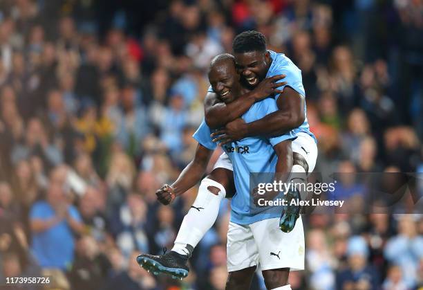 Benjani of Manchester City Legends celebrates with team mate Micah Richards after scoring a goal during the Vincent Kompany testimonial match between...