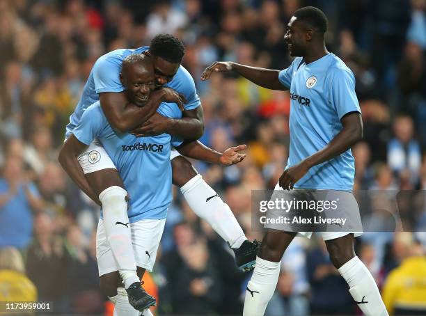 Benjani of Manchester City Legends celebrates with team mate Micah Richards after scoring a goal during the Vincent Kompany testimonial match between...