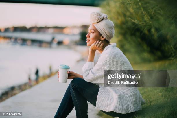 muslimische mädchen genießen kaffee am fluss - women's issues stock-fotos und bilder