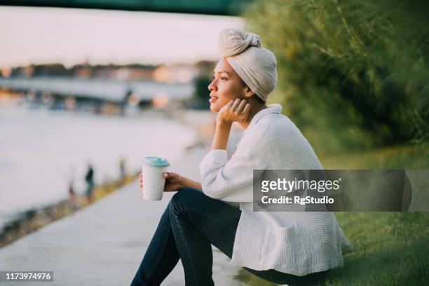 muslim girl enjoying coffee by a river - different religions stock pictures, royalty-free photos & images