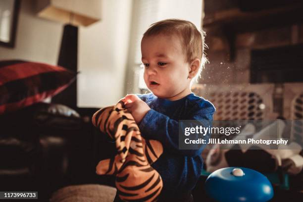 portrait of a male 2 year old toddler playing with toys /puppet in middle class home - mouth smirk stock pictures, royalty-free photos & images