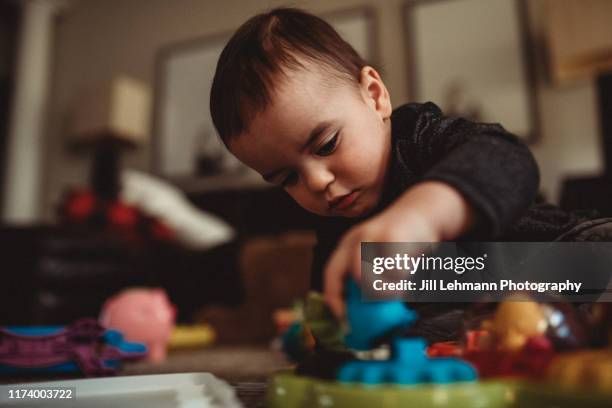 portrait of a male 2 year old toddler playing with toys in middle class home - mouth smirk stock pictures, royalty-free photos & images