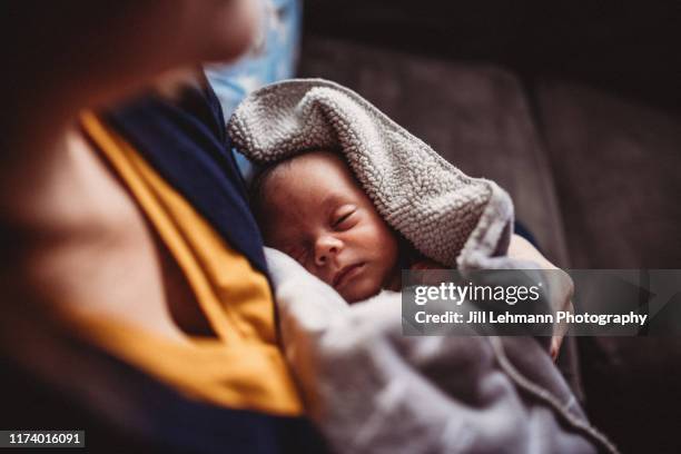 newborn baby is held by mother with dramatic window light and blankets - premature stock pictures, royalty-free photos & images
