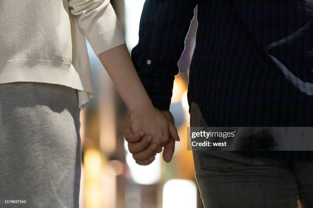 Back view of men and women holding hands in downtown at night