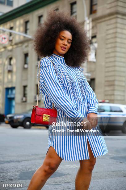 Raissa Santana arrives at the Libertine show at Spring Studios for New York Fashion Week wearing a blue and white dress with a red purse on September...