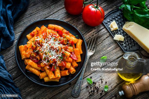 rigatoni pasta with tomato sauce shot on rustic wooden table - pasta tomato basil stock pictures, royalty-free photos & images