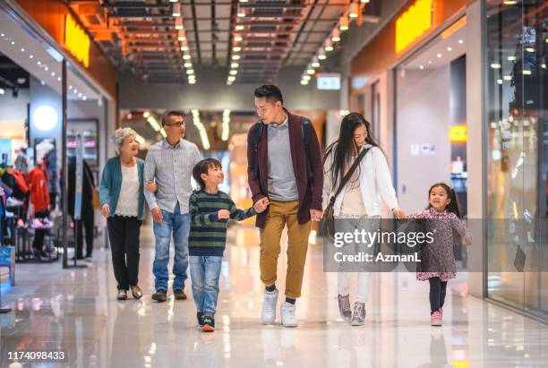 multi-generation chinese family enjoying evening at the mall - family mall stock pictures, royalty-free photos & images