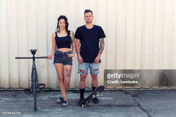 portrait of a tattooed young couple with bicycle and skateboard - white rapper stock pictures, royalty-free photos & images
