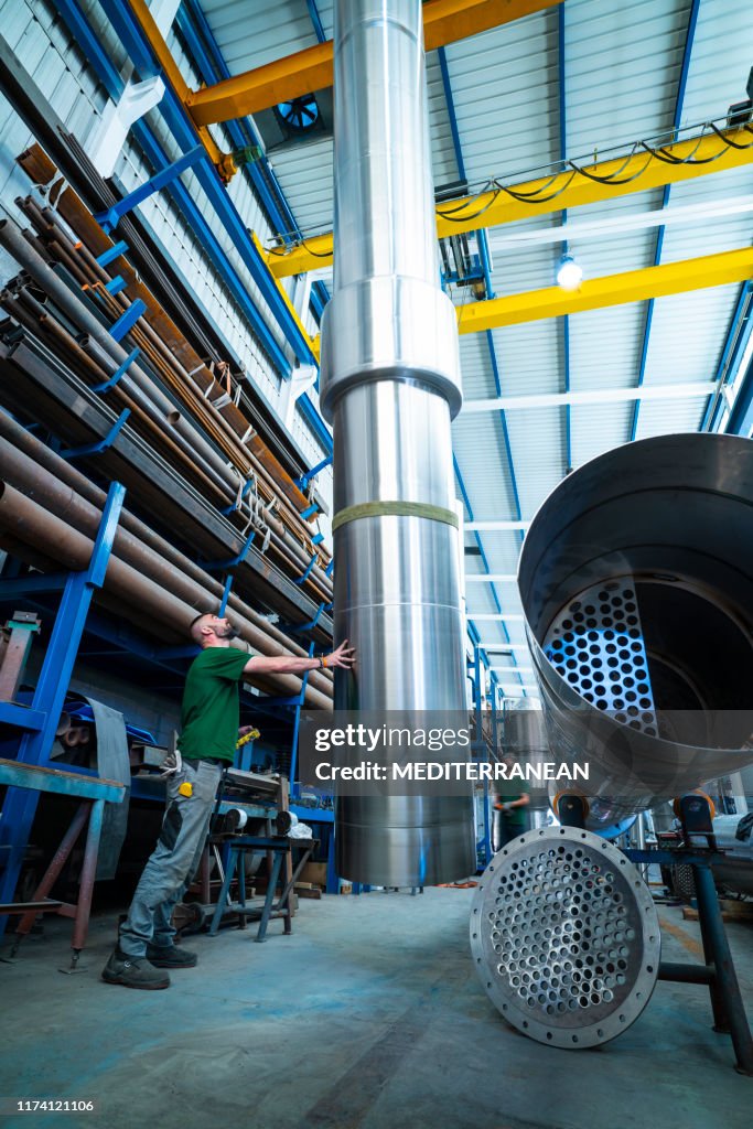 Industrial worker moving with crane big pipes